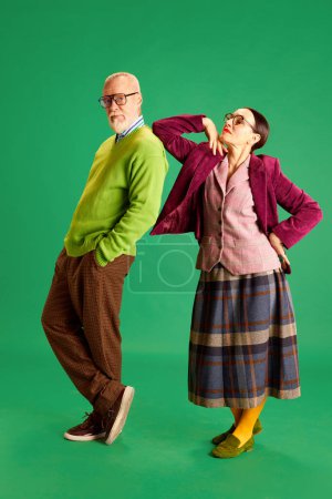 Foto de Elegante, hermoso, amoroso hombre y mujer, pareja de ancianos en ropa casual posando sobre fondo de estudio verde. Concepto de belleza y moda, relación, estilo moderno, edad - Imagen libre de derechos