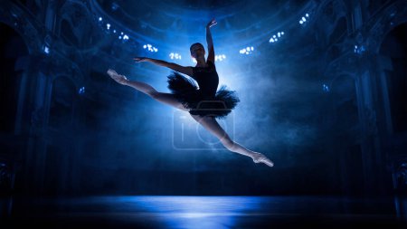 Photo for Beautiful, elegant, artistic young woman, ballerina in motion, jumping, dancing on theater stage with spotlights. Concept of classical dance, art and grace, beauty, choreography, inspiration - Royalty Free Image