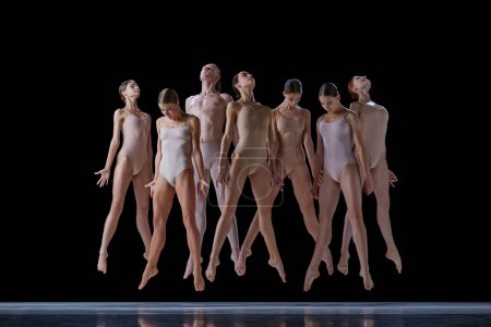 Foto de Grupo de jóvenes, bailarines de ballet en trajes beige actuando, bailando en el escenario sobre fondo negro. Concepto de danza clásica y moderna, belleza, creatividad, arte, inspiración - Imagen libre de derechos