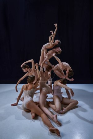 Téléchargez les photos : Gracieux, beaux jeunes gens, danseurs de ballet en body beige dansant sur fond noir. Concept de danse classique et moderne, beauté, créativité, art, théâtre - en image libre de droit