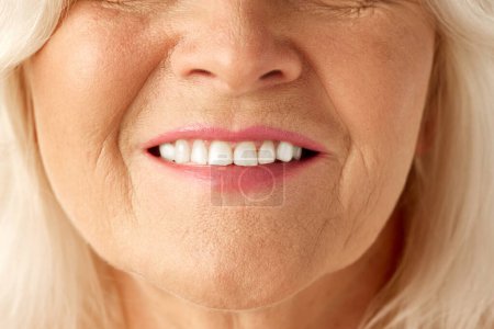 Téléchargez les photos : Image en gros plan de la bouche féminine, souriant avec des dents blanches. Modèle senior avec rides. Soins dentaires. Concept de beauté naturelle, processus de vieillissement, beauté âgée, cosmétologie, soins de la peau - en image libre de droit