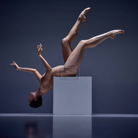 Photo for Graceful. tender, attractive woman, ballerina in beige bodysuit posing, sitting on cube against blue studio background. Concept of classical dance, art and grace, beauty, choreography, inspiration - Royalty Free Image