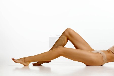Photo for Cropped image of slender, tanned, smooth female legs against white studio background. Depilation, epilation, laser hair removal. Concept of natural beauty, body and skin care, health, sport, wellness. - Royalty Free Image