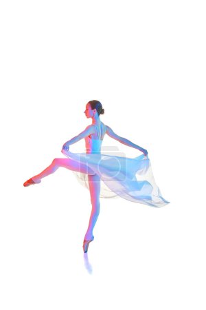 Foto de Joven mujer artística, bailarina en body girando sobre punta, bailando con tela transparente aislada sobre fondo blanco en neón. Concepto de belleza, danza clásica, arte, elegancia, coreografía - Imagen libre de derechos