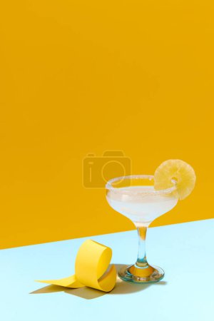 Téléchargez les photos : Cocktail de margarita aigre-doux populaire avec une décoration de tranches de citron isolée sur fond jaune. Concept de boissons alcoolisées, fête, vacances, bar, mix. Affiche. Espace de copie pour la publicité - en image libre de droit