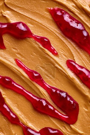 Photo for Close-up of smooth peanut butter and berry jam. Creamy, golden-brown peanut butter with a smooth wavy texture. Concept of food, breakfast, healthy eating and snacks, organic, homemade products - Royalty Free Image