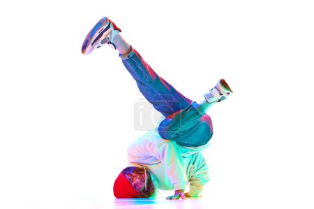 Téléchargez les photos : Image dynamique de l'homme dans sa trentaine de hip hop danseur en mouvement isolé sur fond de studio blanc au néon. Concept de danse contemporaine, style de rue, mode, passe-temps, jeunesse. Publicité - en image libre de droit