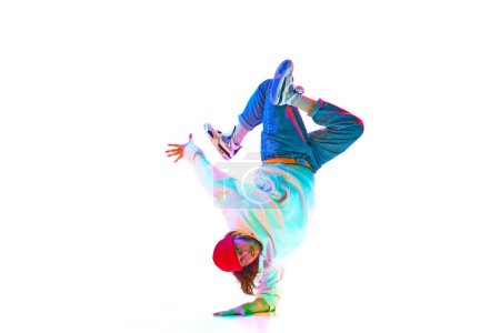 Foto de Hombre yo9ung flexible en ropa deportiva bailando hip hop, breakdance aislado sobre fondo de estudio blanco en luz de neón. Concepto de danza contemporánea, estilo callejero, moda, hobby, juventud. Anuncio - Imagen libre de derechos