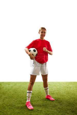 Photo for Full-length of young motivated woman, football player in uniform standing with ball on grass field isolated on white background. Concept of sport, competition, action, success. Copy space for ad - Royalty Free Image