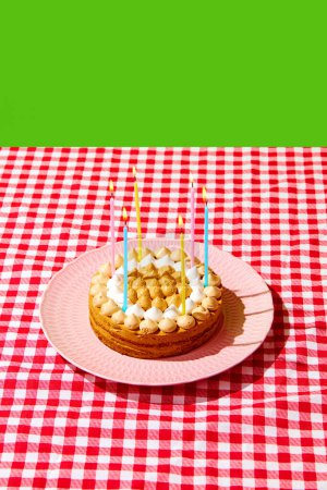 Téléchargez les photos : Tarte crémeuse sucrée et délicieuse, gâteau aux bougies d'anniversaire isolé sur une nappe à carreaux sur fond vert. Concept de nourriture, desserts, fête d'anniversaire, fête, boulangerie. Style pop art. Affiche - en image libre de droit
