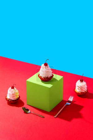 Foto de Pasteles dulces con decoración de cereza en cubo verde sobre fondo rojo azul. Concepto de comida, postres, celebración de cumpleaños, fiesta, panadería. Estilo pop art. Copia espacio para el anuncio. Cartel - Imagen libre de derechos