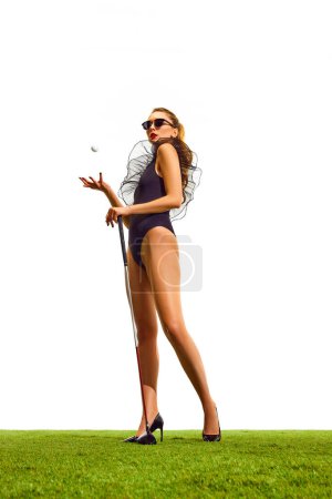 Photo for Full-length of beautiful, stylish young girl with slim body, in elegant bodysuit and heels posing with gold club isolated over white background. Concept of sport, hobby, beauty and fashion, relaxation - Royalty Free Image