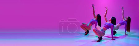 Téléchargez les photos : Des jeunes femmes élégantes, des danseuses séduisantes dansant à talons hauts dansent sur fond de studio rose sous la lumière du néon. Concept de passe-temps, style de danse contemporaine, art, beauté, créativité, élégance - en image libre de droit