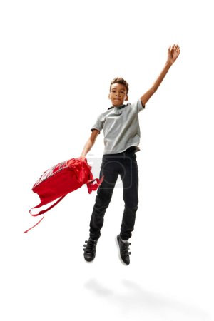 Photo for Cute curly African-American boy jumping with joy because of he back to school. Child study and learn for preschool. Online education. Concept of childhood, International Knowledge Day. Copy space. Ad - Royalty Free Image