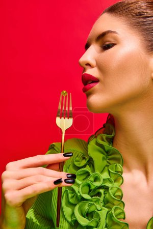 Photo for Close up portrait of attractive lady holds impaled on fork vitamin, tablet, pill and want to eat it isolated red background. Concept of medicine, viruses, immune system, selfcare, healthcare. - Royalty Free Image