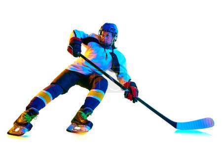 Téléchargez les photos : Image dynamique de la jeune femme, payeuse de hockey en mouvement pendant le jeu, l'entraînement, jouer sur fond blanc sous la lumière du néon. Concept de sport professionnel, compétition, jeu, action, passe-temps - en image libre de droit