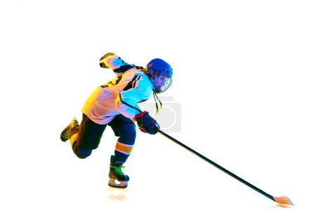 Foto de Campeón. Chica joven, jugador de hockey en movimiento, vistiendo uniforme, jugando con palo contra fondo blanco en luz de neón. Concepto de deporte profesional, competición, juego, acción, hobby - Imagen libre de derechos