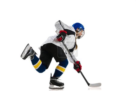 Téléchargez les photos : Jeune fille, joueuse de hockey professionnelle en mouvement pendant le match, jouant isolée sur fond blanc. Des réussites. Concept de sport professionnel, compétition, jeu, action, passe-temps, succès - en image libre de droit