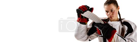 Foto de Retrato de niña hermosa, jugador de hockey en uniforme de pie con palo aislado sobre fondo blanco. Concepto de deporte profesional, competición, juego, hobby. Espacio vacío para insertar el texto - Imagen libre de derechos