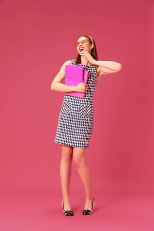 Foto de Chica joven feliz, alegre, sonriente con libros y cuadernos contra fondo de estudio rosa. Emoción. Concepto de juventud, emociones humanas, educación, estilo de vida, moda - Imagen libre de derechos