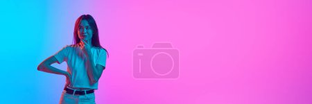 Photo for Portrait of young woman posing against gradient pink blue studio background in neon light. Concept of human emotions, lifestyle, youth culture, facial expression. Banner. Empty space to insert text - Royalty Free Image