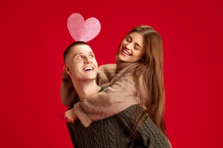 Photo for Playful, young, happy couple, man and woman, boyfriend and girlfriend having fun against red studio background. Concept of love, relationship, Valentines Day, emotions, lifestyle - Royalty Free Image