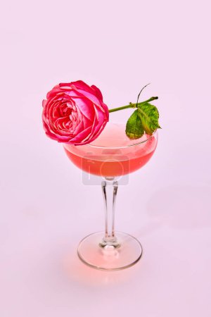 Téléchargez les photos : Verre avec délicieux cocktail aigre-doux à la fleur de rose isolée sur fond rose. Concept de boissons alcoolisées, goût, fête, célébration - en image libre de droit