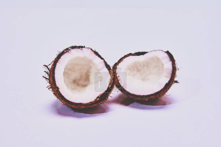 Téléchargez les photos : Noix de coco coupée en deux sur fond clair. Produits biologiques. Concept de nature, nourriture, goût, tropical. Espace vide pour insérer du texte - en image libre de droit