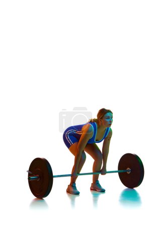 Photo for Young woman, athlete in motion, training, lifting heavy weights, barbell against white background in neon light. Concept of sport, strength, gym, healthy lifestyle, power and endurance, weightlifting. - Royalty Free Image