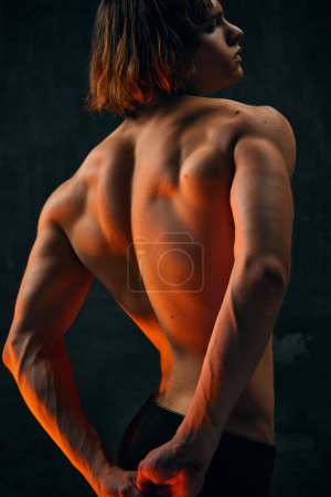 Photo for Relief, muscular, athletic male back. Shirtless model with fit body posing against dark studio background. Concept of mens beauty, health, body art and aesthetics, care, sportive lifestyle - Royalty Free Image