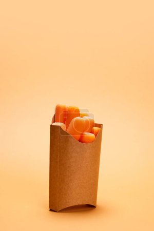 Foto de Corte, zanahorias frescas y deliciosas colocadas en el embalaje de cartón para papas fritas sobre fondo naranja. Concepto de alimentos saludables, nutrición, dieta, productos orgánicos, dieta, vitaminas vegetales. Póster, anuncio - Imagen libre de derechos