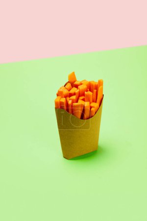 Téléchargez les photos : Couper, carottes fraîches placées dans un emballage carton pour les frites sur fond vert. Concept d'alimentation saine, nutrition, alimentation, produits biologiques, alimentation, vitamines végétales. Affiche, annonce - en image libre de droit
