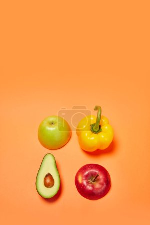 Photo for Yellow sweet pepper, green and red apple, avocado against orange background. Flat lay. Concept of healthy food, nutrition, diet, organic products, diet, vegetable vitamins. Poster, ad - Royalty Free Image
