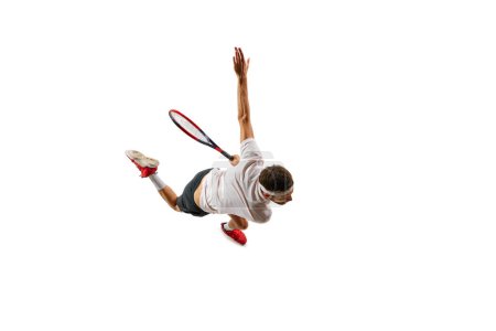 Téléchargez les photos : Vue de dessus. Jeune homme concentré et compétitif pratiquant le tennis, en mouvement avec raquette, jouant isolé sur fond blanc. Concept de sport, passe-temps, mode de vie actif et sain, compétition - en image libre de droit