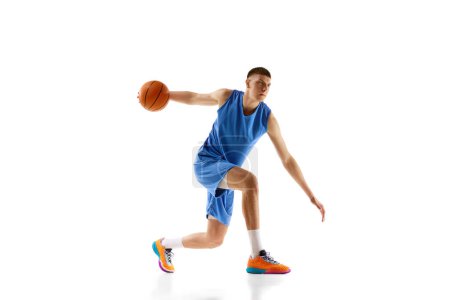Photo for Dynamic image of young man in blue uniform, basketball player in motion during game, dribbling ball isolated on white background. Concept of sport, competition, match, championship, health, action. Ad - Royalty Free Image
