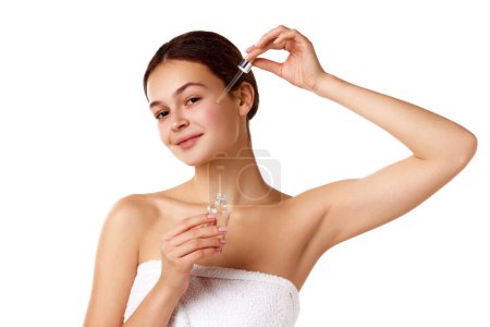 Photo for Young girl with smooth, healthy well-kept face, taking care after skin, applying serum against white background. Concept of natural female beauty, skin care, cosmetology and cosmetics - Royalty Free Image