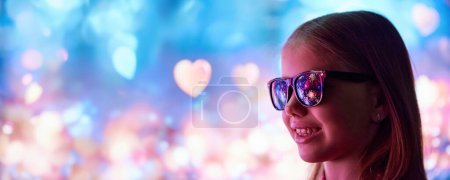 Foto de Feliz niña sonriente, niño alegre en gafas de sol mirando en la celebración de vacaciones con fuegos artificiales. Reflexión sobre las gafas. Concepto de Navidad, infancia, sueños, fantasía, felicidad. Banner - Imagen libre de derechos