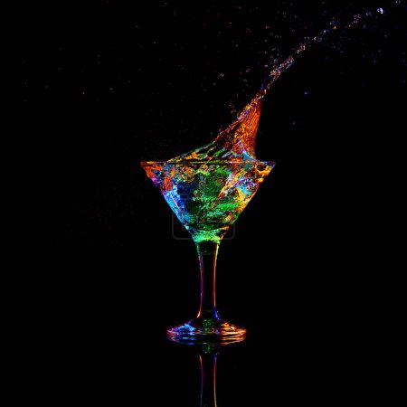 Photo for Ice cube falling down into glass with martini cocktail against dark background with neon light. Traditional taste. Concept of alcohol drink, nightclub, party, taste, celebration. - Royalty Free Image