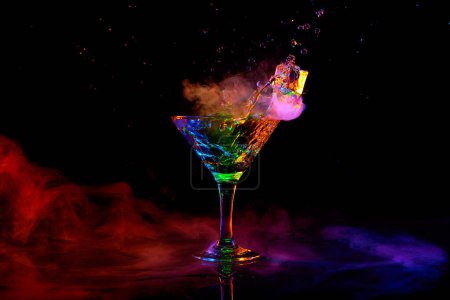 Photo for Glass with delicious cocktail with martini against dark background with neon light with smoke. Pouring liquid, splashes. Concept of alcohol drink, nightclub, party, taste, celebration. - Royalty Free Image