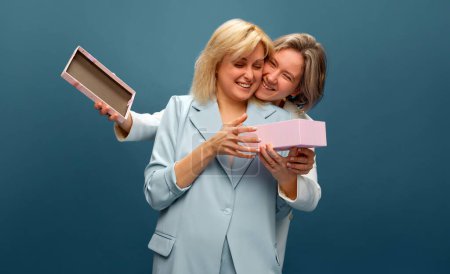 Photo for Happy smiling lesbian couple celebrating Romanic holidays, receiving presents against studio background. Concept of lgbt community, love, Valentines day, freedom, acceptance, February 14th - Royalty Free Image