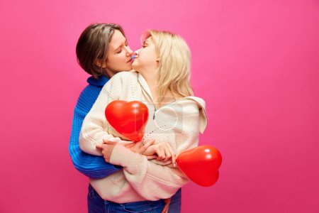 Photo for Happy young women, lesbian couple celebrating romantic holiday, kissing over pink studio background. Concept of lgbt community, love, Valentines day, freedom, acceptance, February 14th - Royalty Free Image