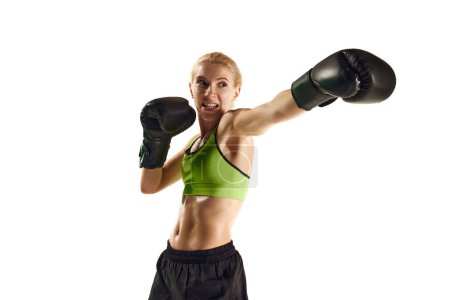 Téléchargez les photos : Un coup de poing. Jeune femme sportive au corps musclé pratiquant la boxe isolée sur fond blanc. Concept de sport, mode de vie actif et sain, force et endurance, soins corporels - en image libre de droit