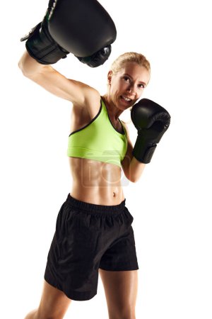 Téléchargez les photos : Un coup de crochet droit. Jeune femme sportive avec un entraînement musculaire mince, boxe isolée sur fond blanc. Concept de sport, mode de vie actif et sain, force et endurance, soins corporels - en image libre de droit