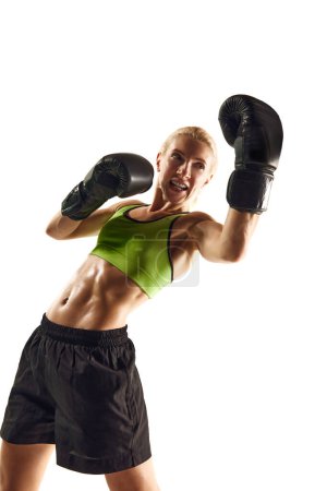 Téléchargez les photos : Coup de poing. Jeune femme avec entraînement musculaire, athlète de boxe pratiquant isolé sur fond blanc. Concept de sport, mode de vie actif et sain, force et endurance, soins corporels - en image libre de droit