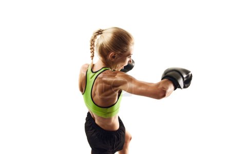 Téléchargez les photos : Vue du dessus de la jeune femme sportive concentrée avec entraînement musculaire du corps, athlète de boxe en mouvement isolé sur fond blanc. Concept de sport, mode de vie actif et sain, force, soins du corps - en image libre de droit