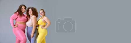 Photo for Beautiful plus size models, young women in comfortable sportswear standing against grey studio background. Concept of sport, body-positivity, weight loss, body and health care, gym. Banner - Royalty Free Image