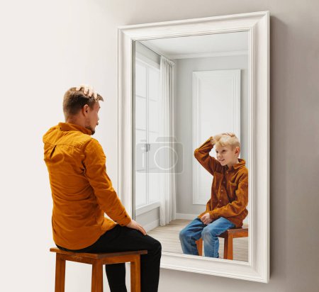 Téléchargez les photos : Homme dans la trentaine assis et regardant dans le miroir avec réflexion son reflet comme un enfant. Souvenirs d'enfance. Collage conceptuel. Concept de présent, passé et futur, âge, cycle de vie, génération, publicité - en image libre de droit