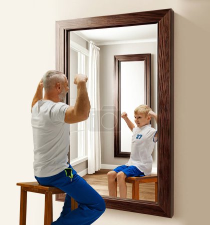 Photo for Senior man in uniform sitting and looking in mirror at hi reflection as child. Ages, ago. Conceptual collage. Concept of present, past and future, age, life cycle, generation, ad - Royalty Free Image