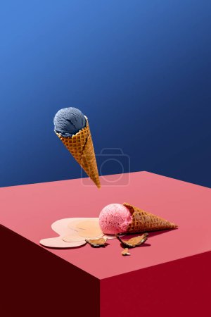 Foto de Helado de arándano levitante en cono de gofre sobre cubo con helado rosa derretido tumbado sobre fondo azul. collage creativo. Concepto de creatividad, arte abstracto, minimalismo, comida - Imagen libre de derechos