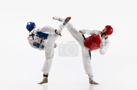 Photo for Athletic, strong young men, taekwondo athletes in motion, fighting, training isolated over white background. Concept of martial arts, combat sport, competition, action, strength, education - Royalty Free Image